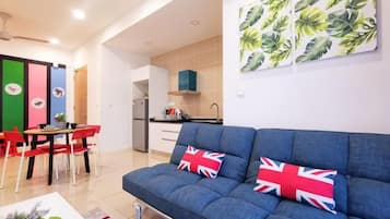 A modern living room with a sofa, red chairs, a dining table, and a kitchen area.