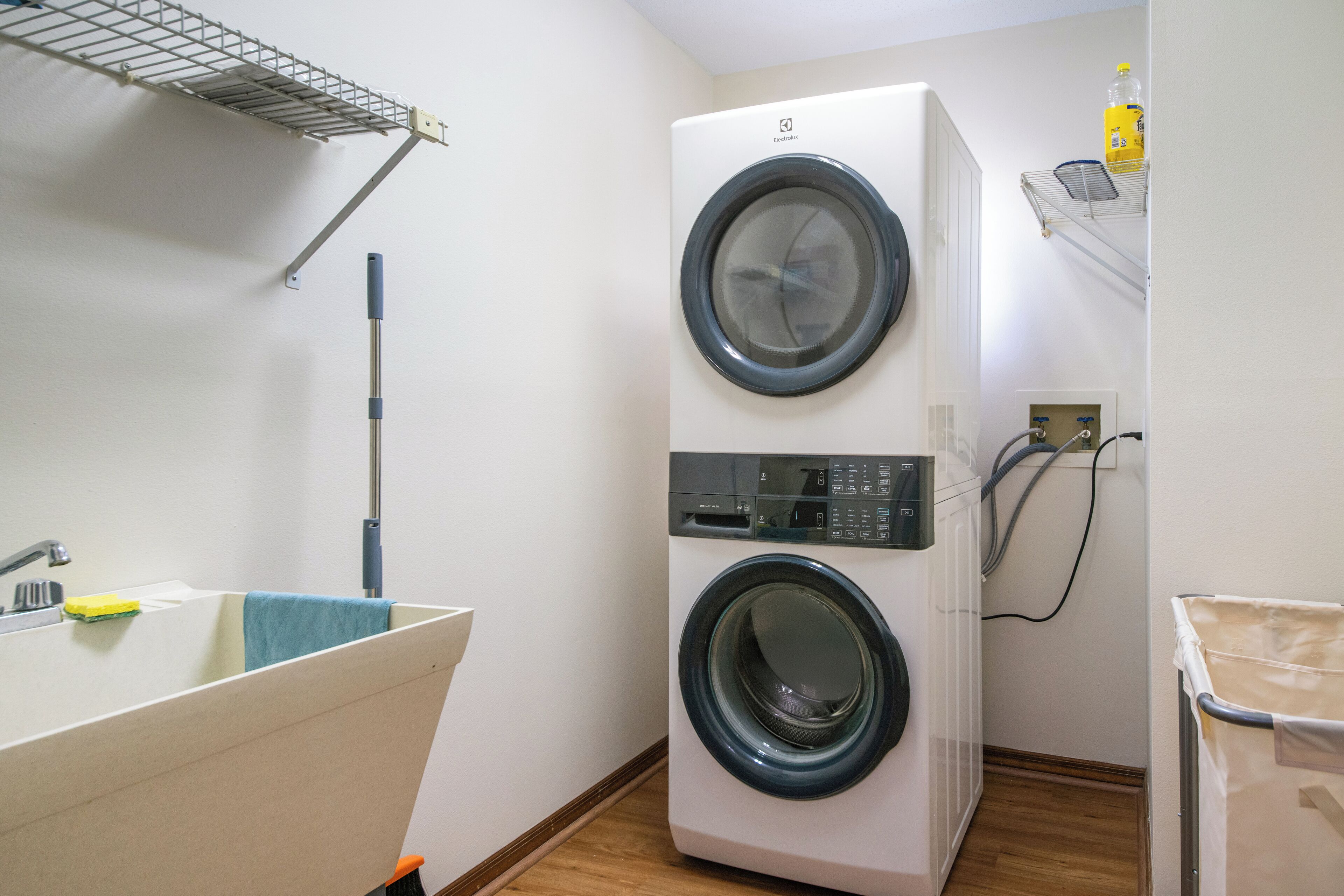 A compact laundry room with a washing machine, a sink, and a mop.