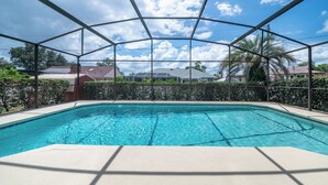 A swimming pool with a clear blue water, surrounded by a metal fence, and houses in the background. - Cozy 4bed 2bth villa - daytona beach  (Deltona)