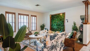A living room with a sofa, a coffee table, and a large plant. - Cozy 4bed 2bth villa - daytona beach  (Deltona)