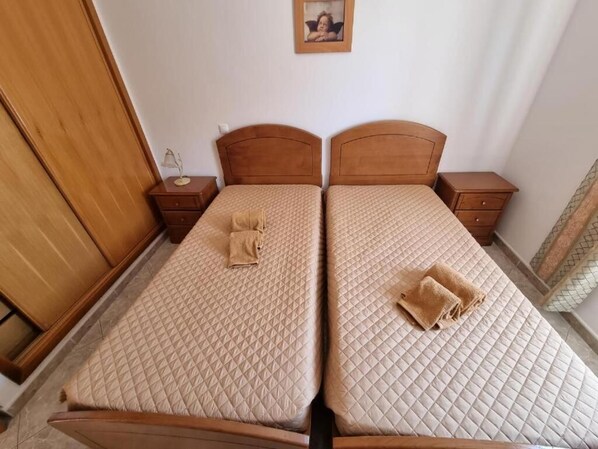 A room with two beds, each with a wooden headboard, a bedside table, and a lamp. - Torre da Aldeia by Umbral (Albufeira)