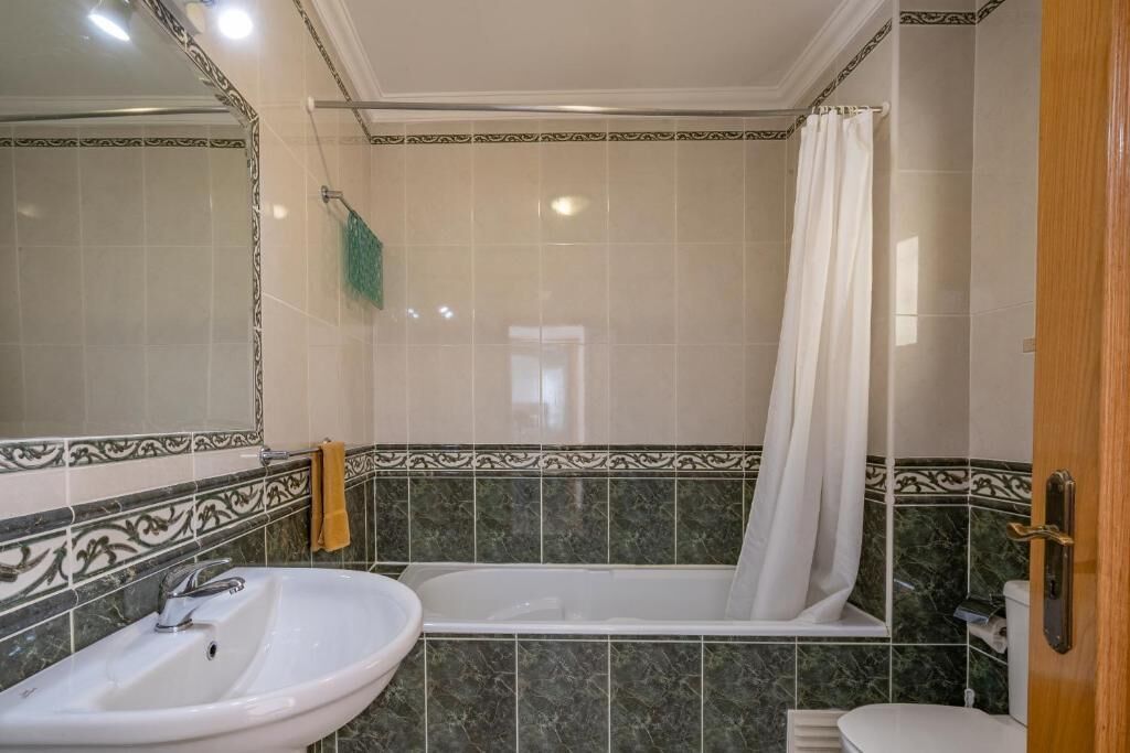 A bathroom with a sink, bathtub, and shower curtain.