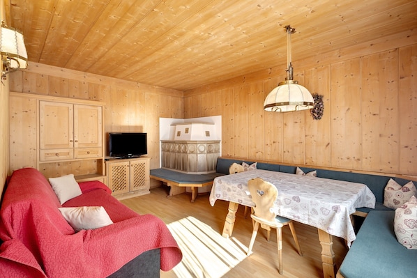 Un intérieur en bois comprenant un canapé, une table, un banc et un téléviseur.