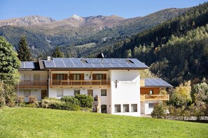 Un hôtel doté de panneaux solaires sur le toit, d’un balcon et offrant une vue sur les montagnes.