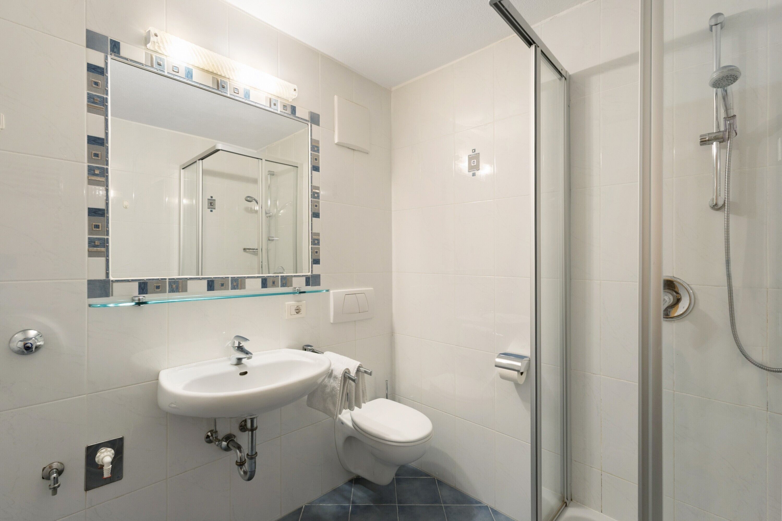 Ein Badezimmer mit Duschkabine aus Glas, Waschbecken in Weiß und Toilette.