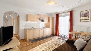 Une cuisine moderne avec des meubles en bois, une cuisinière encastrée et un coin repas comprenant une table et des chaises.