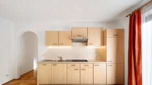 Une cuisine moderne avec des meubles en bois, une cuisinière encastrée et une fenêtre ornée de rideaux rouges.