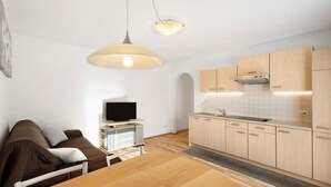 Un espace de vie compact comprenant un coin cuisine, un coin repas et un coin salon avec un téléviseur.