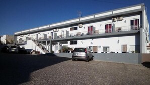 A multi-story building with a central staircase, a car parked in front, and a clear blue sky. - Guest House RSA by Umbral (Loulé)