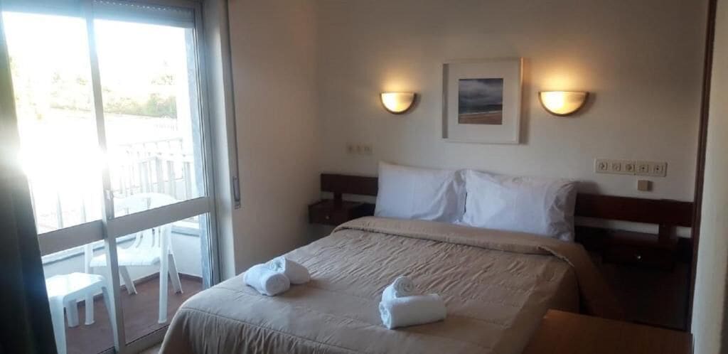 Habitación de hotel con cama, dos lámparas de noche, una ventana y vistas al exterior.
