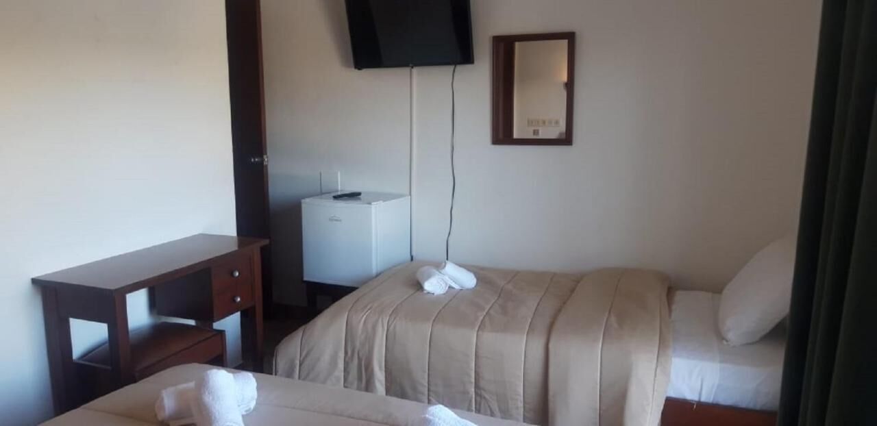 Hotellihuone, jossa on kaksi sänkyä, työpöytä, televisio ja pieni kaappi.
