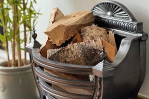 Un porte-bois métallique doté d’un motif décoratif et contenant plusieurs bûches.