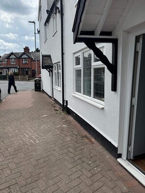 A residential building with a white exterior, a black door, and a window with a white frame. - Cottage - Sleeps 4 - Pets Ok - Patio - Parking (Middlewich)