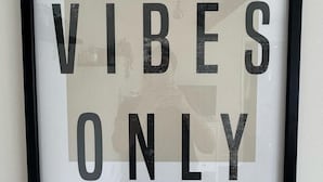 Un letrero en marco con el texto 'GOOD VIBES ONLY' en una pared.