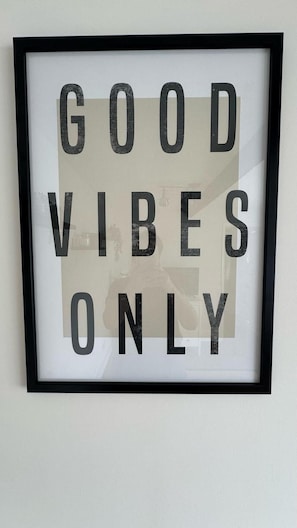 Un panneau encadré, affiché sur un mur, sur lequel on peut lire : « SEULEMENT LES BONNES VIBES ».