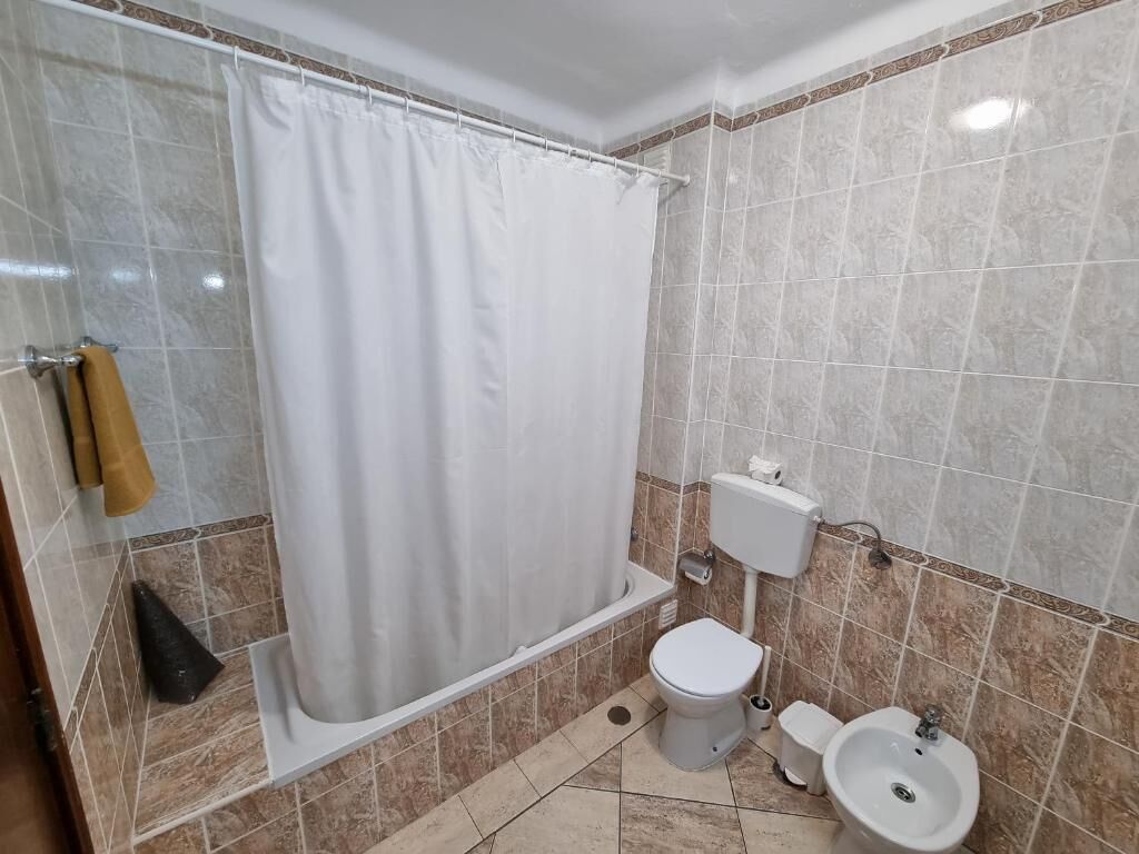 A bathroom with a shower, toilet, bidet, and sink.