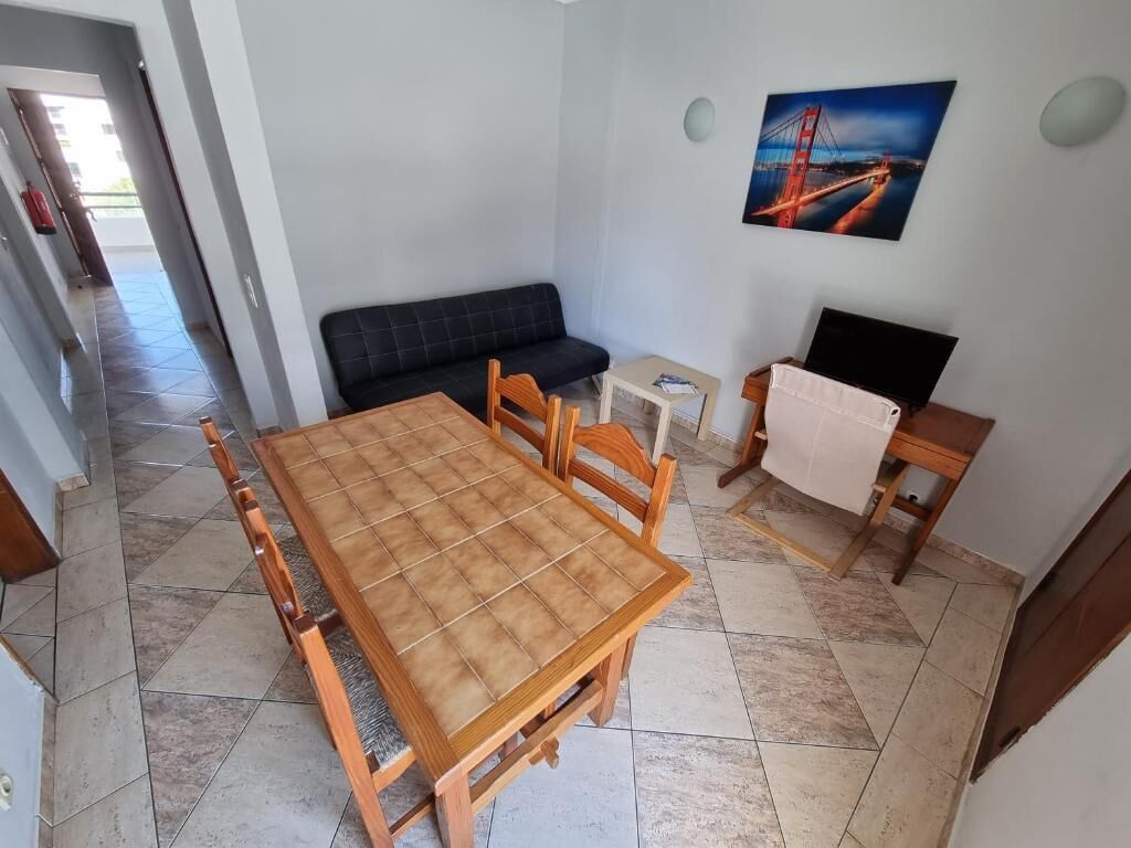 A dining area with a wooden table and chairs, a sofa, and a television.