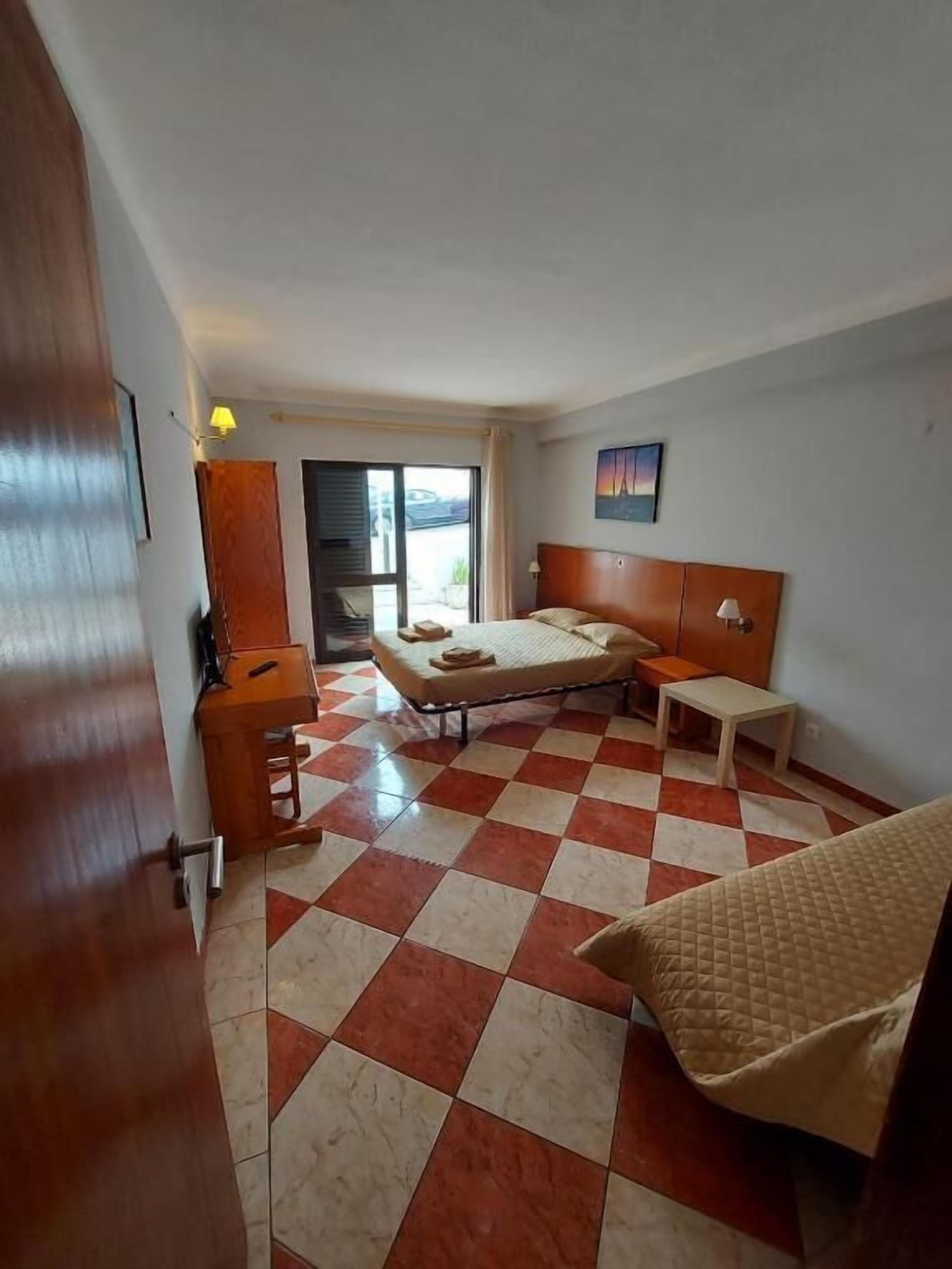 Een hotelkamer met een geruite vloer, een bed, een bureau en een stoel.
