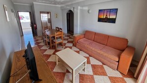 A living room with a checkered floor, a sofa, a coffee table, and a television. - Cerro Atlântico by Umbral (Albufeira)