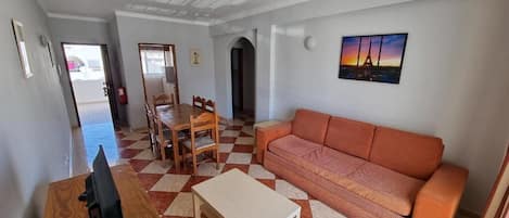 Una sala de estar con piso a cuadros, un sofá, una mesa de centro y un televisor.