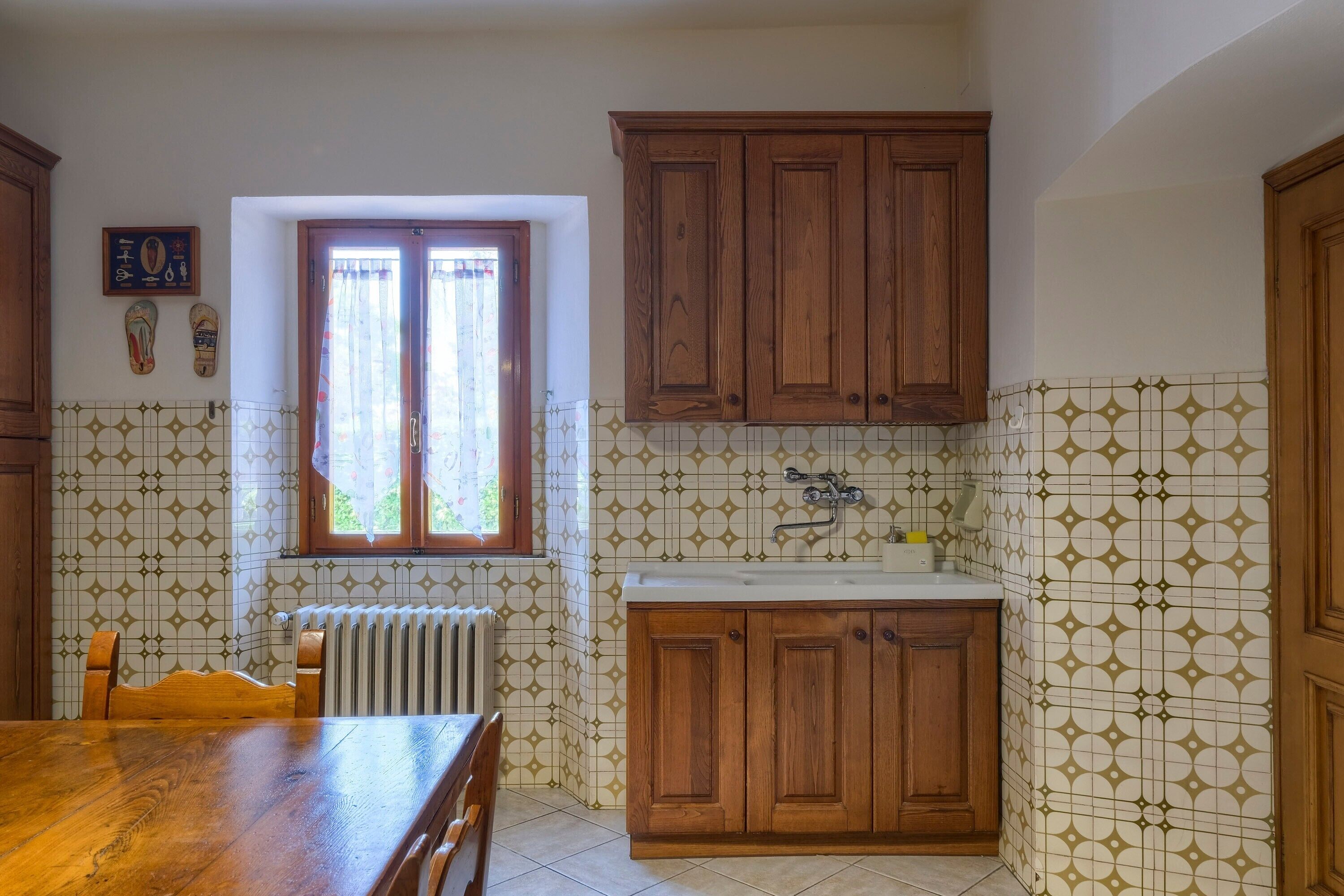 A kitchen with wooden cabinets, a window, and patterned tile walls.