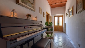 A grand piano in a hallway with framed pictures on the walls, a potted plant, and a door leading to another room. - Holiday Home 'L'aia Dì Trippa All'Aria Mugello' with Private Garden and Wi-Fi (Borgo san Lorenzo)