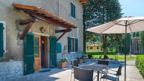 A stone building with a wooden pergola, outdoor seating, and a large umbrella. - Holiday Home 'L'aia Dì Trippa All'Aria Mugello' with Private Garden and Wi-Fi (Borgo san Lorenzo)