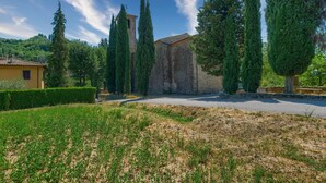 A courtyard with a stone building, tall cypress trees, and a yellow house. - Holiday Home 'L'aia Dì Trippa All'Aria Mugello' with Private Garden and Wi-Fi (Borgo san Lorenzo)