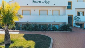 Un hotel de varios pisos llamado "Recavão da Gáve" con fachada blanca, balcones y un área de entrada empaveda con una palmera.