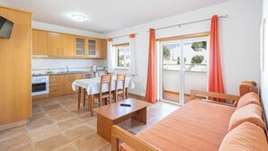 Un espacio habitable compacto con kitchenette, comedor y sofá.