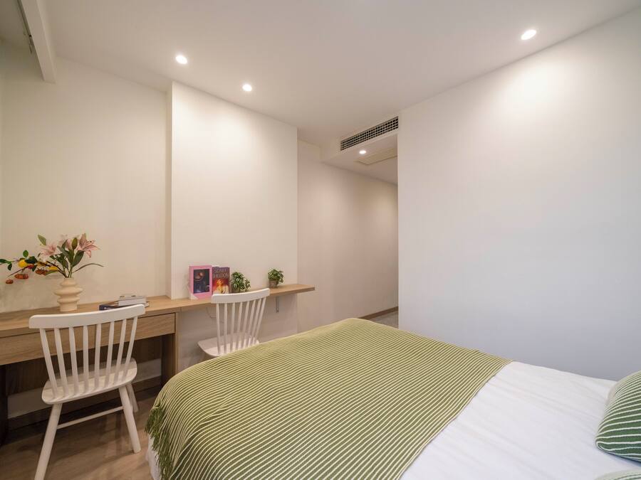 A bedroom with a bed, a desk, and a chair.
