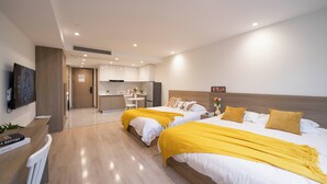 Une chambre d’hôtel moderne équipée de deux lits, d’un bureau et d’une kitchenette.