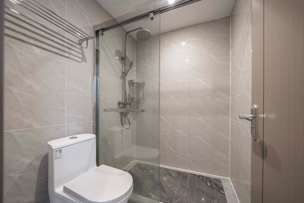 A modern bathroom with a glass-enclosed shower, a toilet, and a glass shower door.