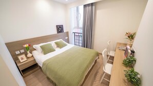 A neatly arranged bedroom with a bed, bedside table, and a desk with chairs. - Book and Bed-QuYang Road (Shanghai)
