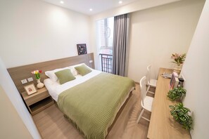 Une chambre bien rangée, avec un lit, une table de chevet et un bureau avec des chaises.