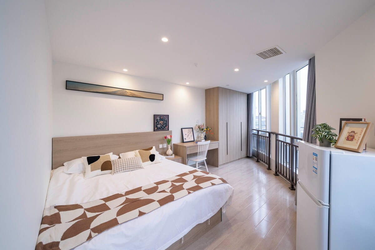 Une chambre moderne avec un grand lit, un bureau et un réfrigérateur.