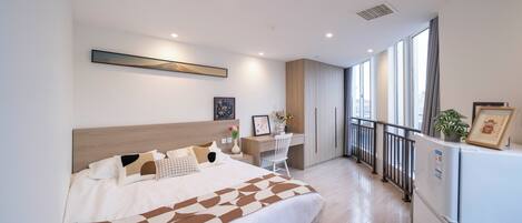 Un dormitorio moderno con una cama grande, un escritorio y un refrigerador.