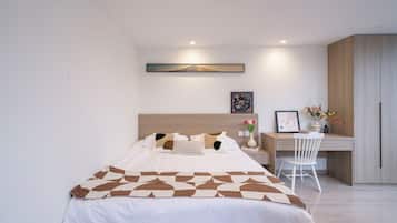 A modern bedroom with a bed, a desk, and a chair.