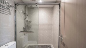 A modern bathroom with a glass-enclosed shower, a toilet, and a sink. - Book and Bed-QuYang Road (Shanghai)