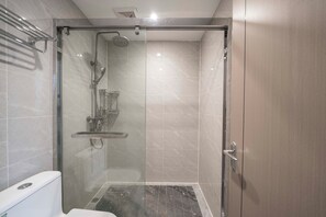 Une salle de bain moderne dotée d’une douche à parois de verre, de toilettes et d’un lavabo.