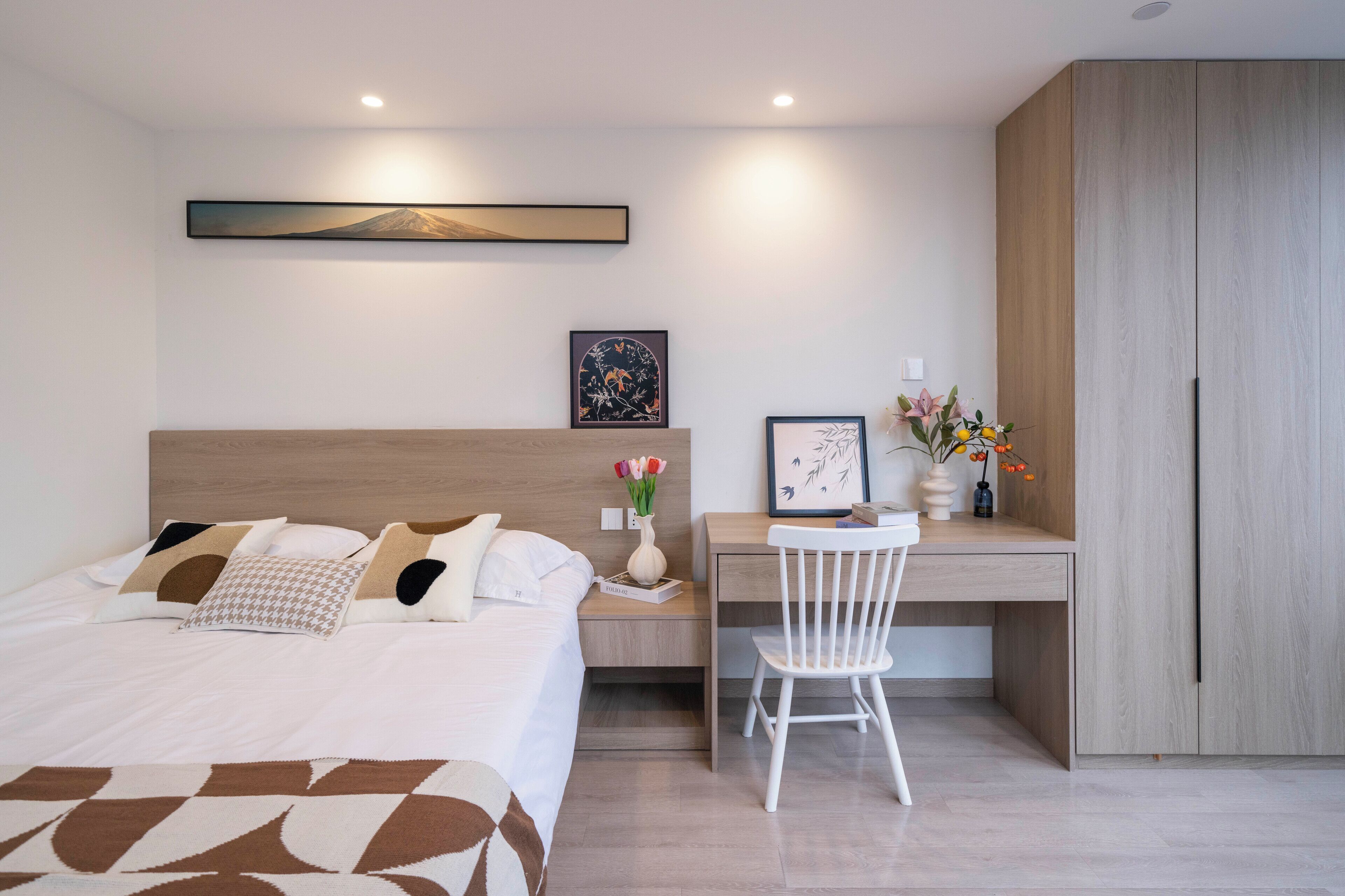 A modern bedroom with a bed, a desk, and a wardrobe.