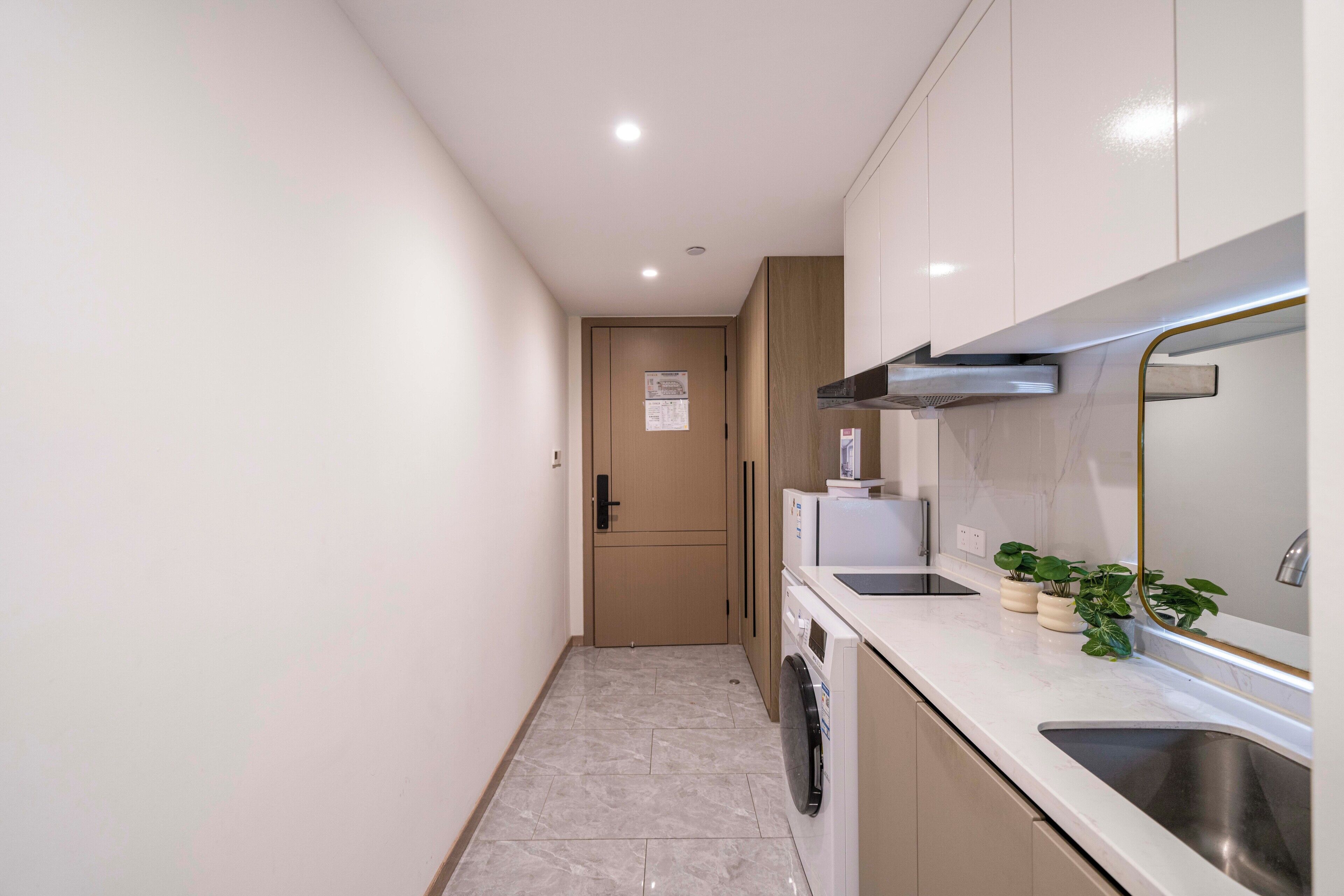 A narrow kitchen with a built-in washer and dryer, a sink, and a stove.