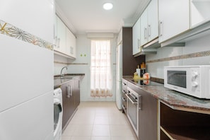 Uma cozinha equipada com máquina de lavar, forno, micro-ondas e armários.