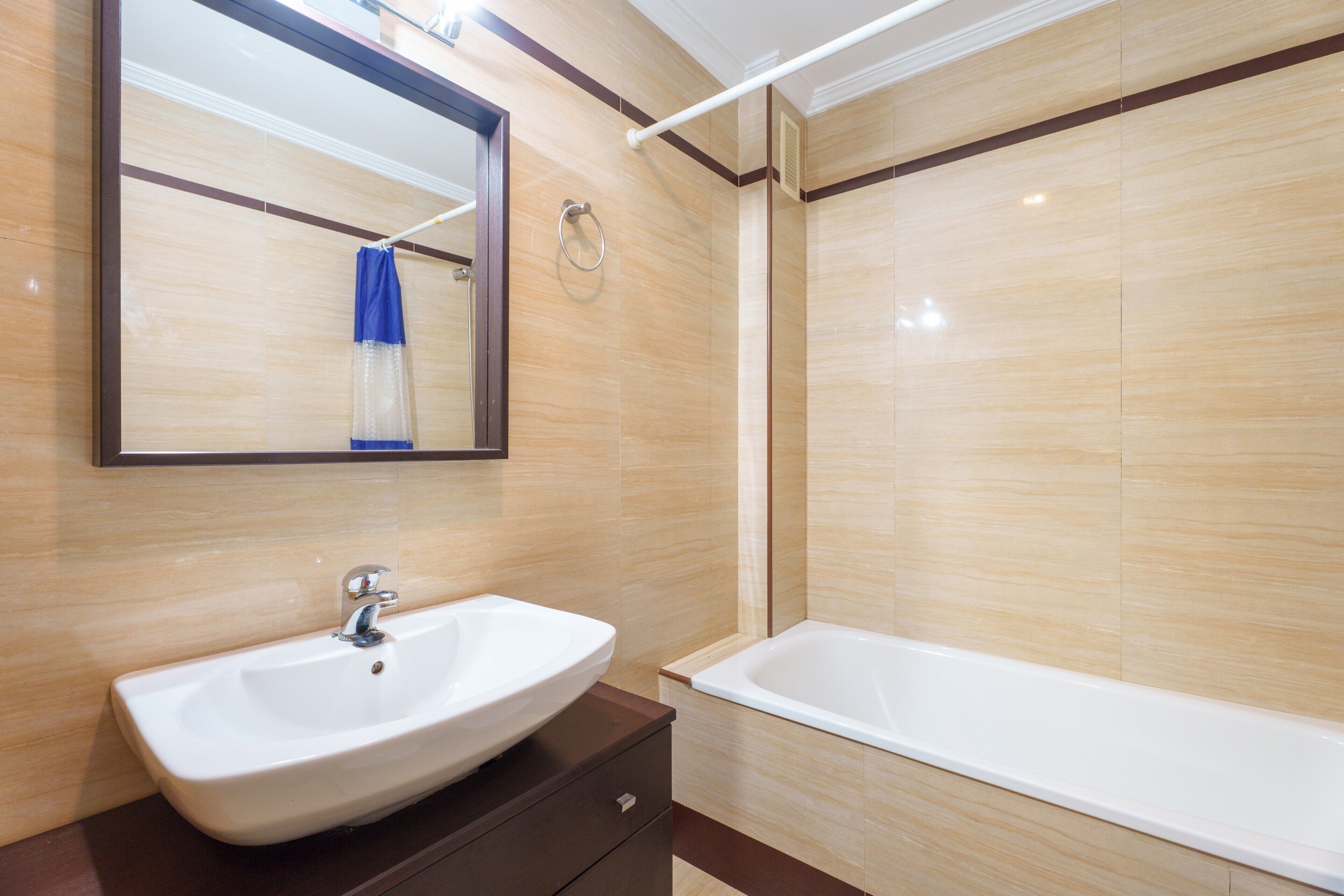 A modern bathroom with a sink, mirror, and bathtub.