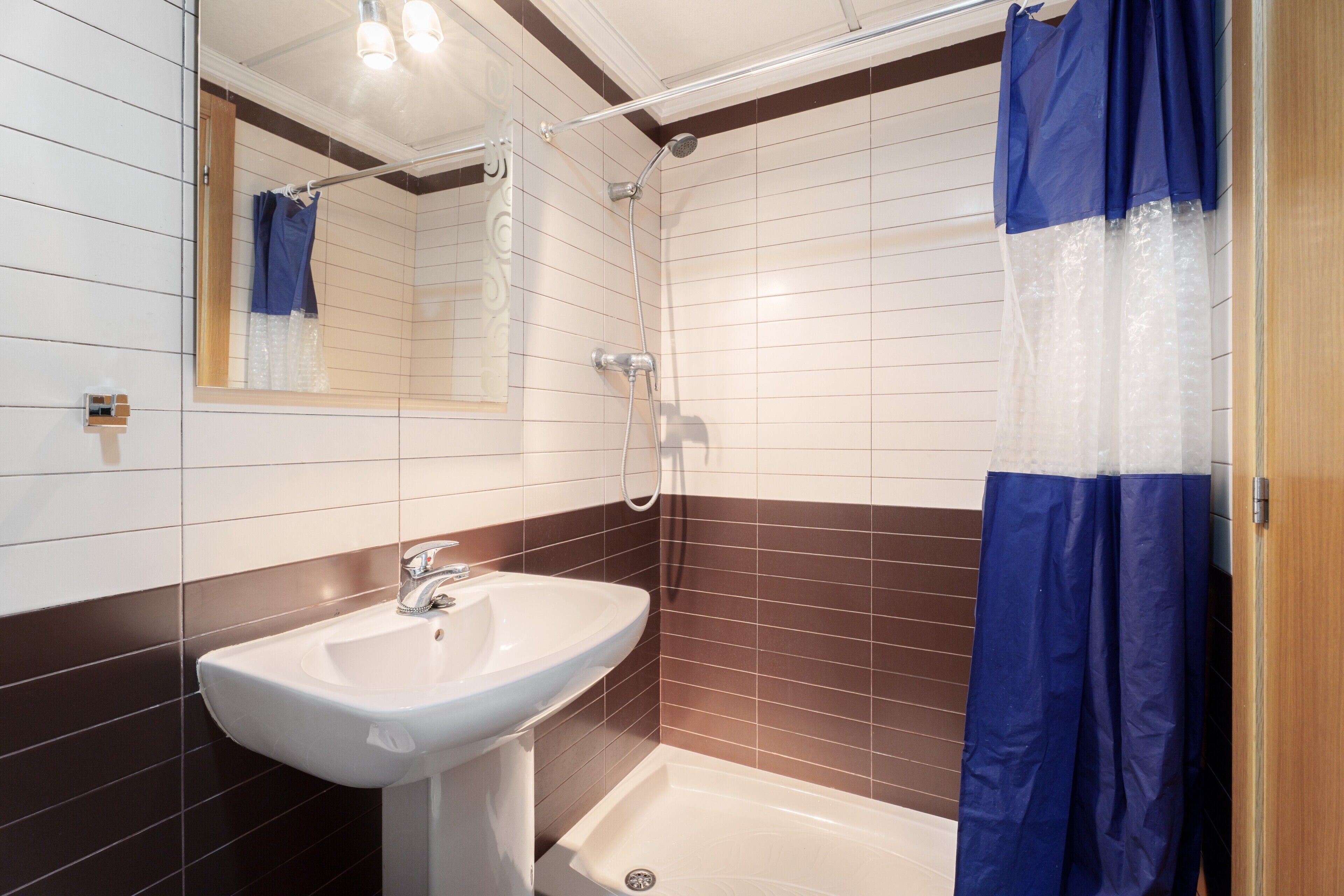 Een badkamer met een wastafel, douche en spiegel.