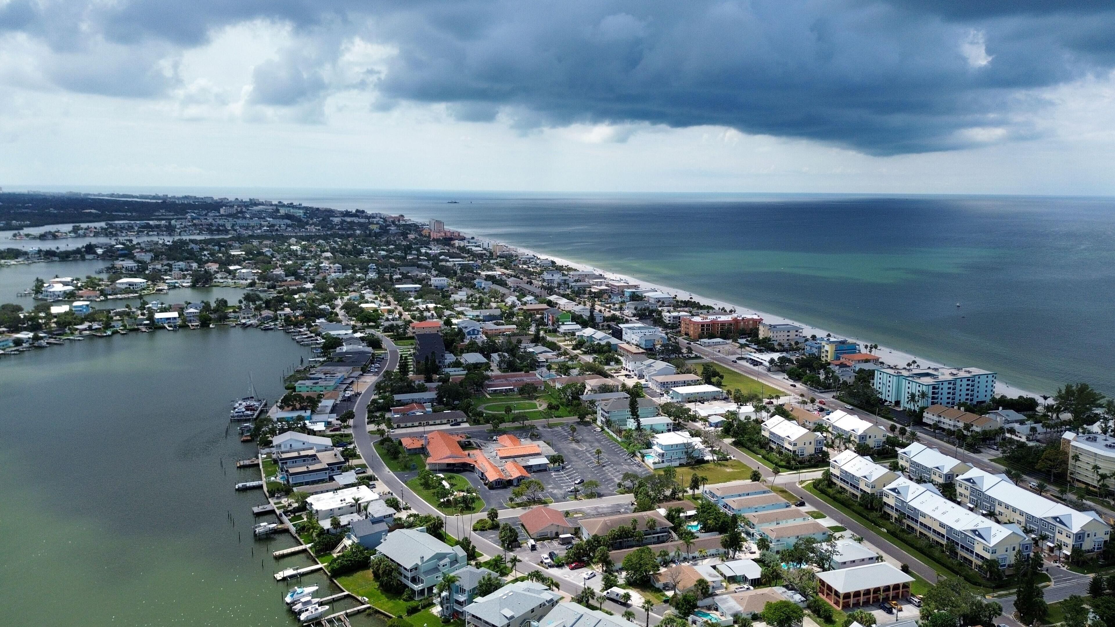 Vue aérienne d’une ville côtière avec un port de plaisance, des immeubles résidentiels et une plage.