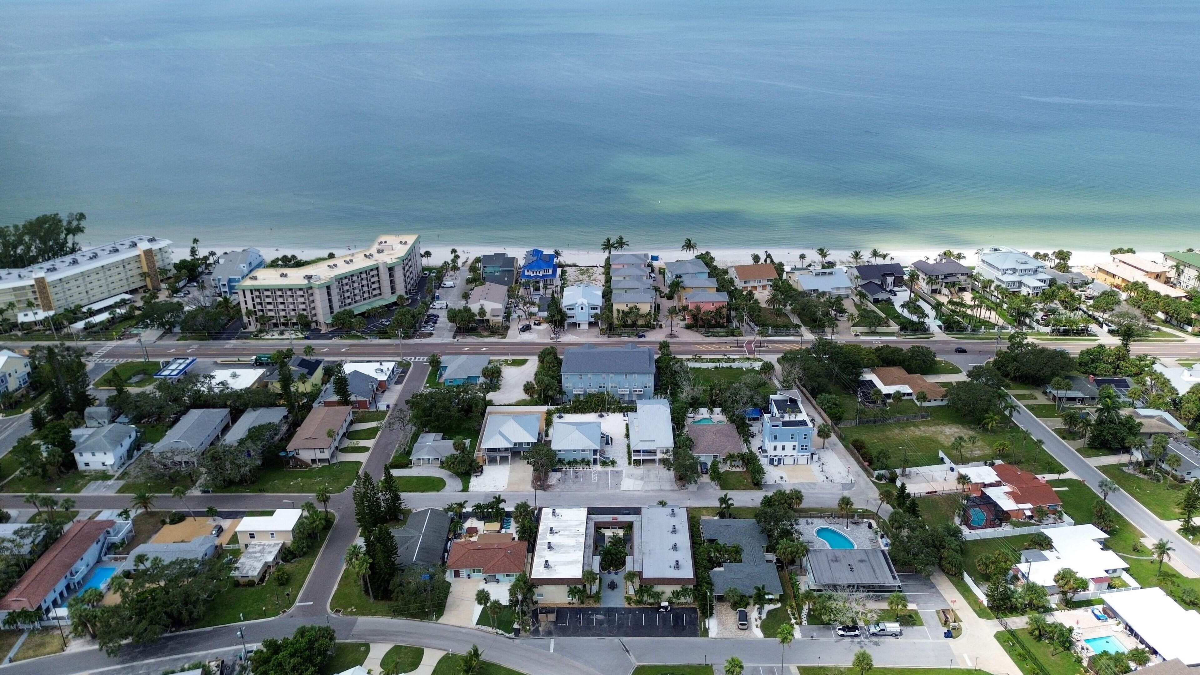 Oversigtsbillede af et kystnært boligområde med huse, en strand og et stort hotel.