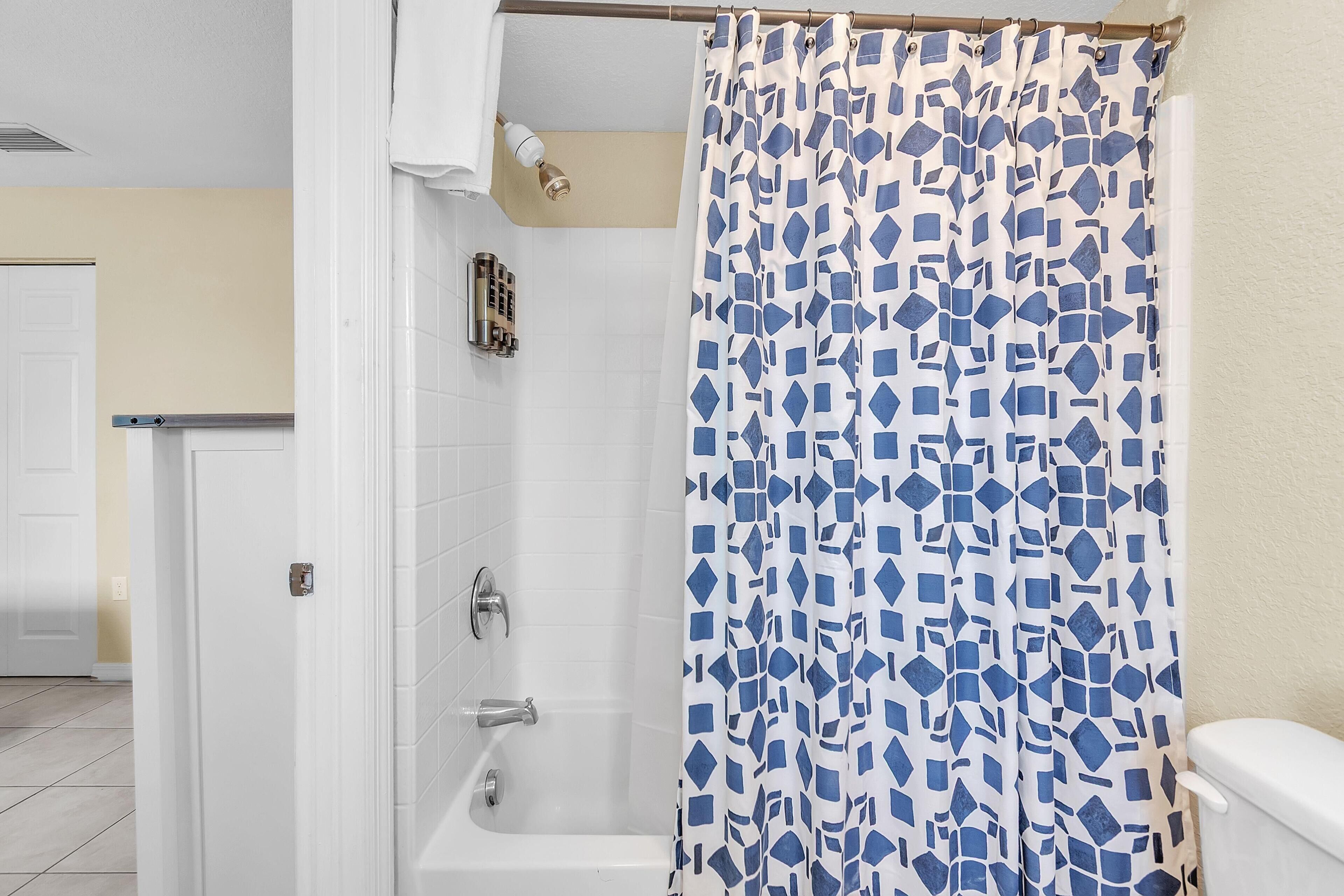 Un baño con cortina de ducha, inodoro y bañera.