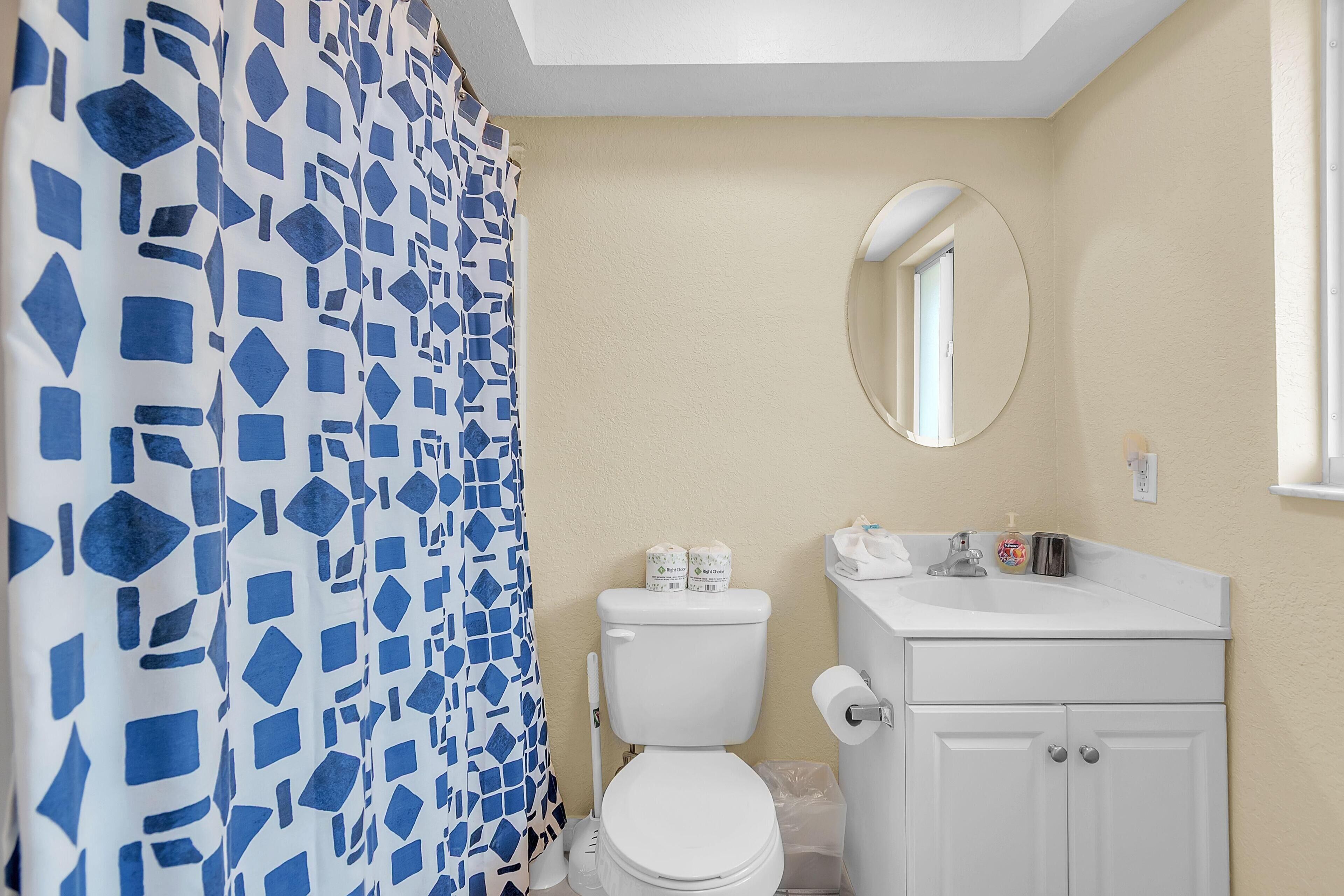 A bathroom with a toilet, sink, mirror, and shower curtain.