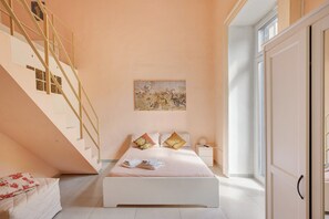 A bedroom with a bed, a nightstand, a painting, a staircase, and a wardrobe. - Holiday Home 'Il Cantuccio Di Diana' with Balcony, Wi-Fi and Air Conditioning (Napoli)